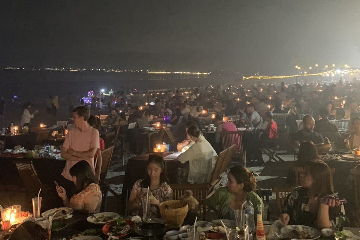 A crowded outdoor dinner by the sea at night