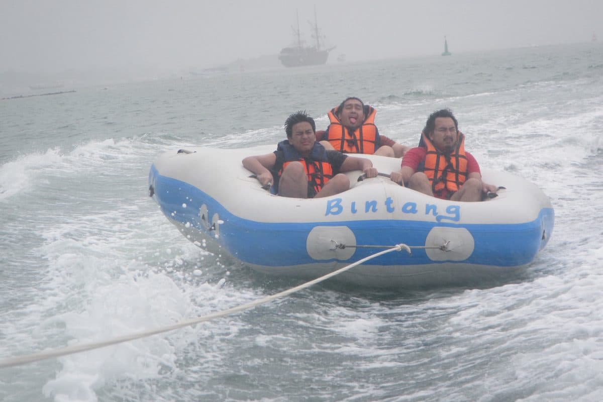 Friends riding an inflatable boat on the waves